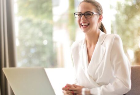 Family Well-being - Laughing businesswoman working in office with laptop