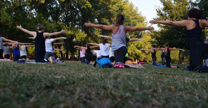 Group Fitness - Women Performing Yoga on Green Grass Near Trees