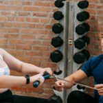 Exercise Motivation - Multiethnic trainer and overweight woman doing exercises with rowing machine together in sport club