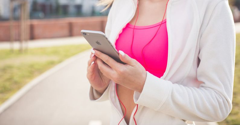 Fitness App - Woman in White Jacket Holding Silver Iphone