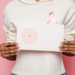 Cancer Prevention - Black female holding paper with painted one breast as symbol of cancer
