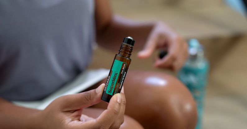 Peppermint Oil - Close-up of Woman Holding a Glass Bottle of Peppermint Essential Oil with a Roller